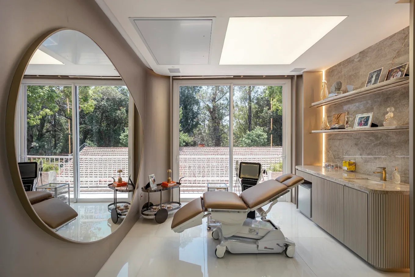 Sala do Med Spa com espelho oval, maca e vista para as árvores